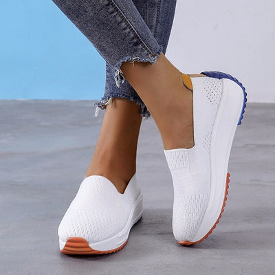 Chaussures blanches décontractées pour femme, semelle épaisse orange et bleue, design tissé, portées avec un jean déchiré. Mode confortable et tendance.