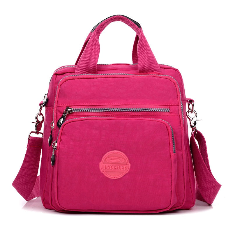 Sac à main rose vif en nylon avec bandoulière amovible, poches zippées multiples, design moderne et pratique pour femme. Accessoire mode tendance.