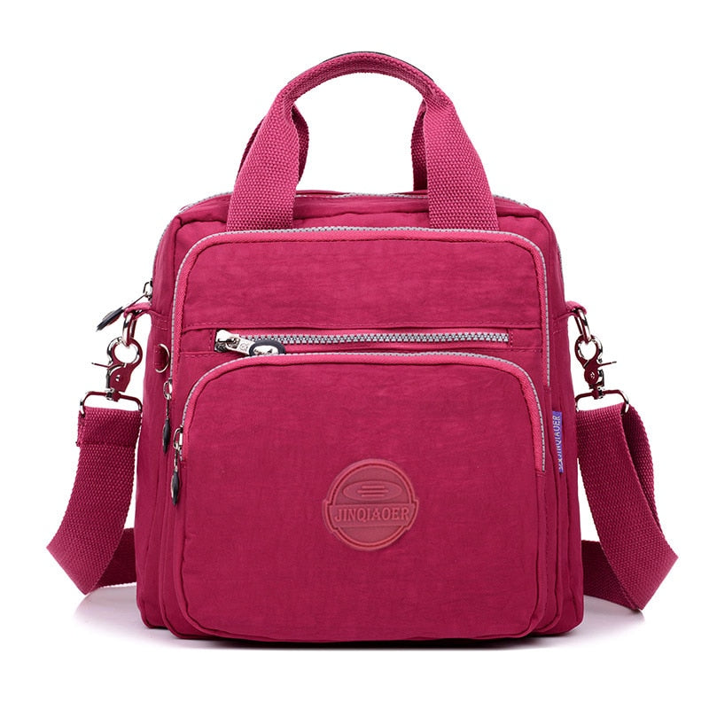 Sac à main rose en toile avec bandoulière réglable, poches zippées et logo. Accessoire mode femme, pratique et tendance.