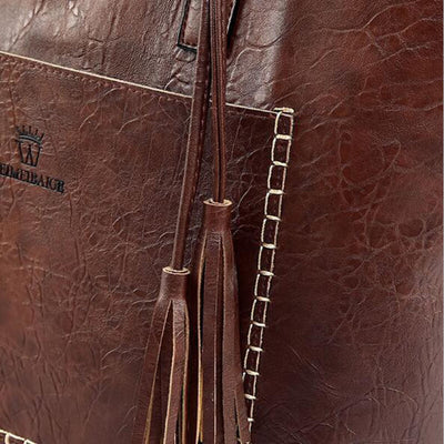 Sac en cuir marron avec coutures blanches contrastantes et franges décoratives. Accessoire mode élégant et tendance pour femmes.
