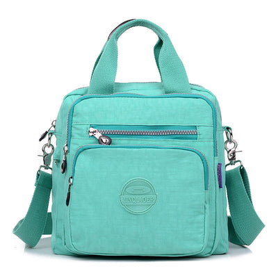 Sac à main vert menthe en toile avec bandoulière amovible, poches zippées et logo. Idéal pour femme, mode, accessoires tendance.