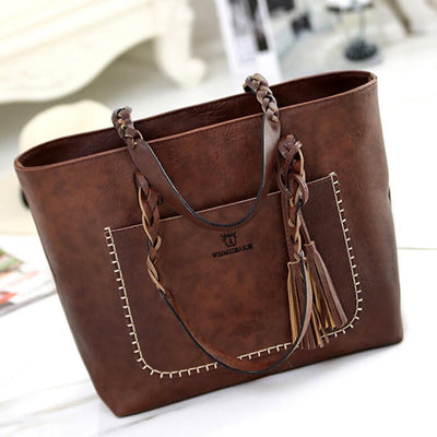 Sac à main en cuir marron avec coutures blanches, anses tressées et pompons décoratifs. Accessoire mode élégant pour femme.