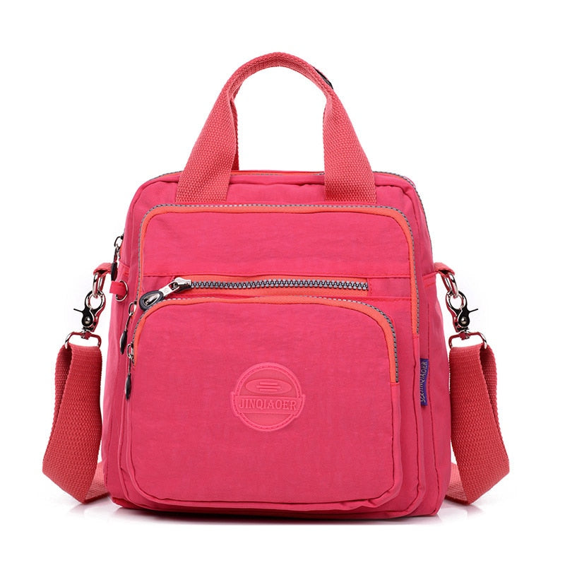 Sac à main rose vif avec bandoulière amovible, poches zippées, design moderne et logo sur le devant. Accessoire mode femme tendance.