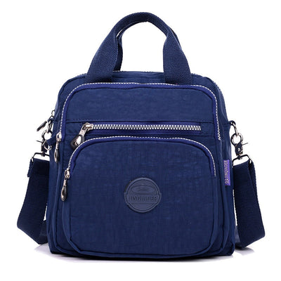 Sac à bandoulière bleu marine en toile, avec plusieurs poches zippées et une poignée supérieure. Design pratique et moderne pour un usage quotidien.