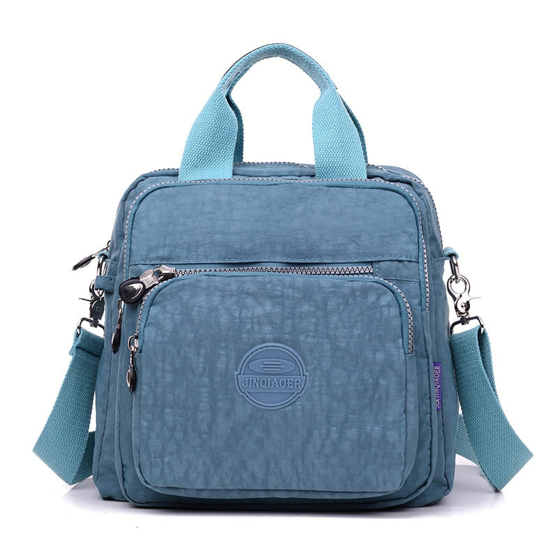 Sac à main bleu en nylon avec bandoulière réglable, poches zippées, design moderne et logo sur le devant. Accessoire mode pratique et tendance.