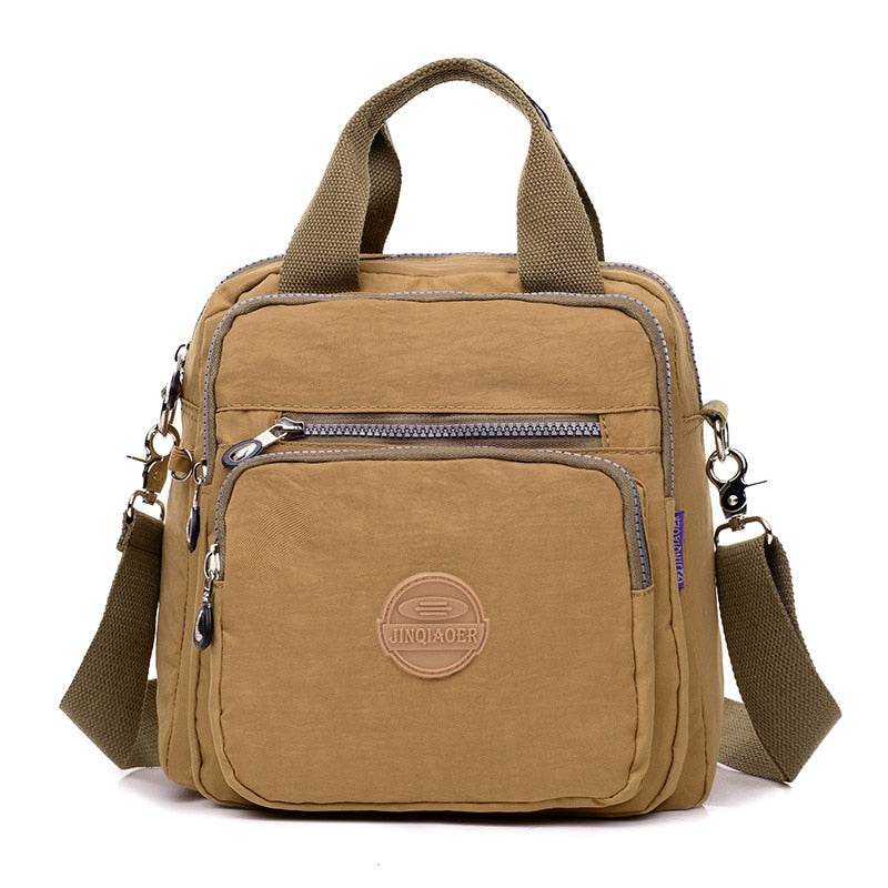 Sac à main en toile beige avec bandoulière réglable, poches zippées et logo circulaire. Style décontracté, idéal pour le quotidien et les voyages.