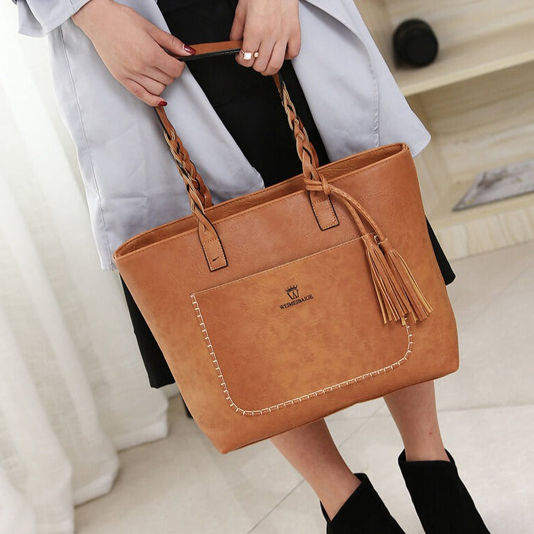 Sac à main en cuir marron avec franges, porté par une femme. Élégant et tendance, idéal pour un look chic et moderne. Accessoire mode incontournable.