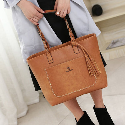 Sac à main en cuir marron avec franges, porté par une femme. Élégant et tendance, idéal pour un look chic et moderne. Accessoire mode incontournable.