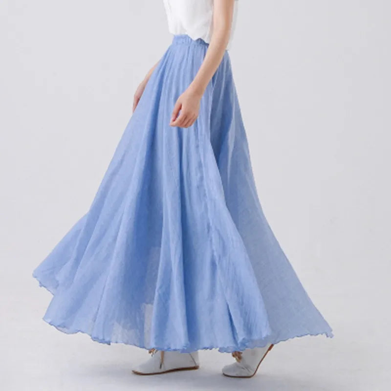 Jupe longue bleue fluide en mousseline, portée avec un haut blanc, style élégant et décontracté, mode féminine printemps-été.