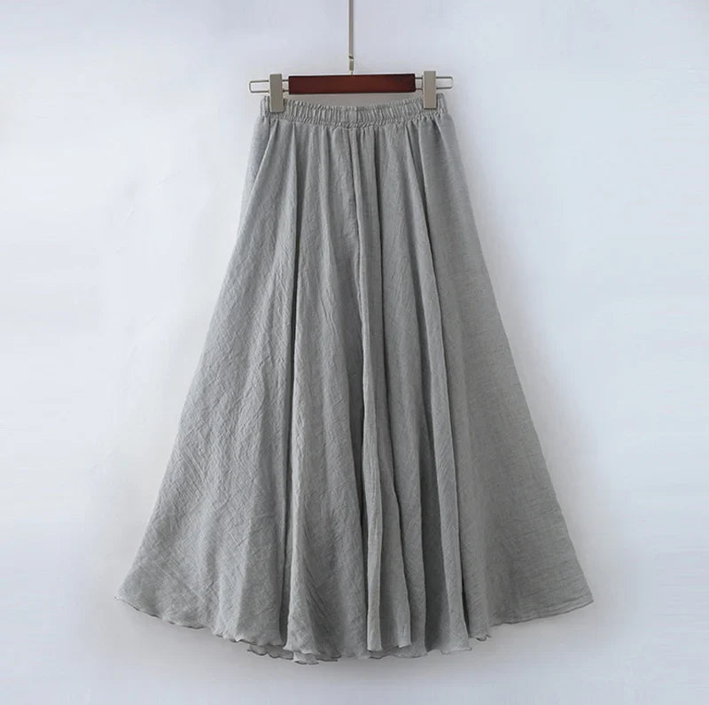 Jupe longue grise en lin, fluide et plissée, suspendue sur un cintre. Mode féminine élégante, vêtement d'été léger et confortable.