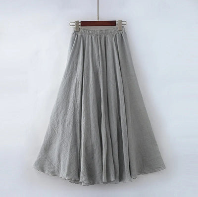 Jupe longue grise en lin, fluide et plissée, suspendue sur un cintre. Mode féminine élégante, vêtement d'été léger et confortable.