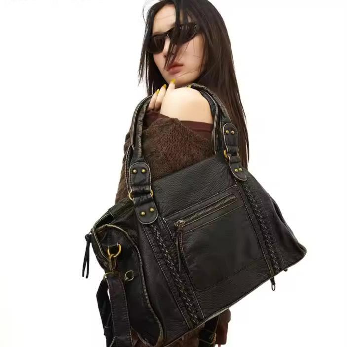 Femme avec sac à main en cuir noir, design élégant avec détails dorés, mode tendance, accessoires féminins, style chic et moderne.