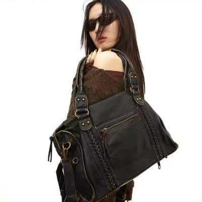 Femme avec sac à main en cuir noir, design élégant avec détails dorés, mode tendance, accessoires féminins, style chic et moderne.