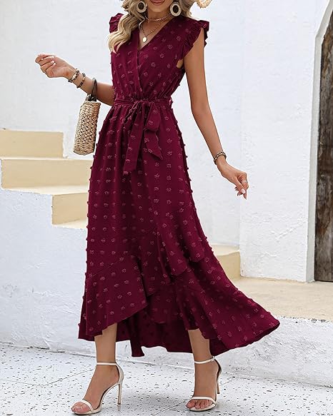 Robe longue bordeaux à volants, sans manches, ceinturée à la taille, portée avec des sandales à talons et un sac en osier. Mode féminine élégante.