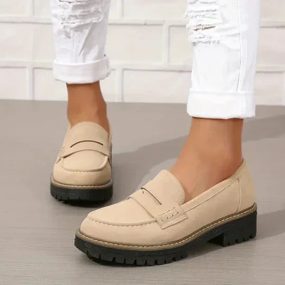 Chaussures mocassins beiges pour femme avec semelles épaisses, portées avec un jean blanc déchiré. Mode féminine, style décontracté, tendance chaussures.