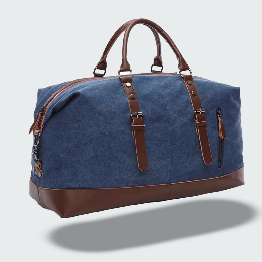 Sac de voyage en toile bleue avec poignées et détails en cuir marron, design élégant et spacieux, idéal pour les escapades et le transport quotidien.