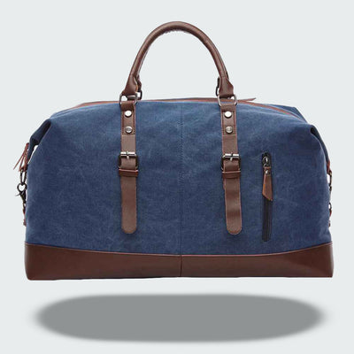 Sac de voyage en toile bleu avec poignées et détails en cuir marron, fermeture éclair, idéal pour week-end, style élégant et pratique.