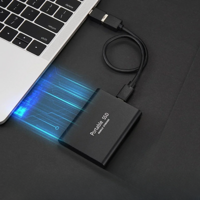 Disque SSD portable connecté à un ordinateur portable via un câble USB, illustrant le transfert de données rapide et sécurisé.