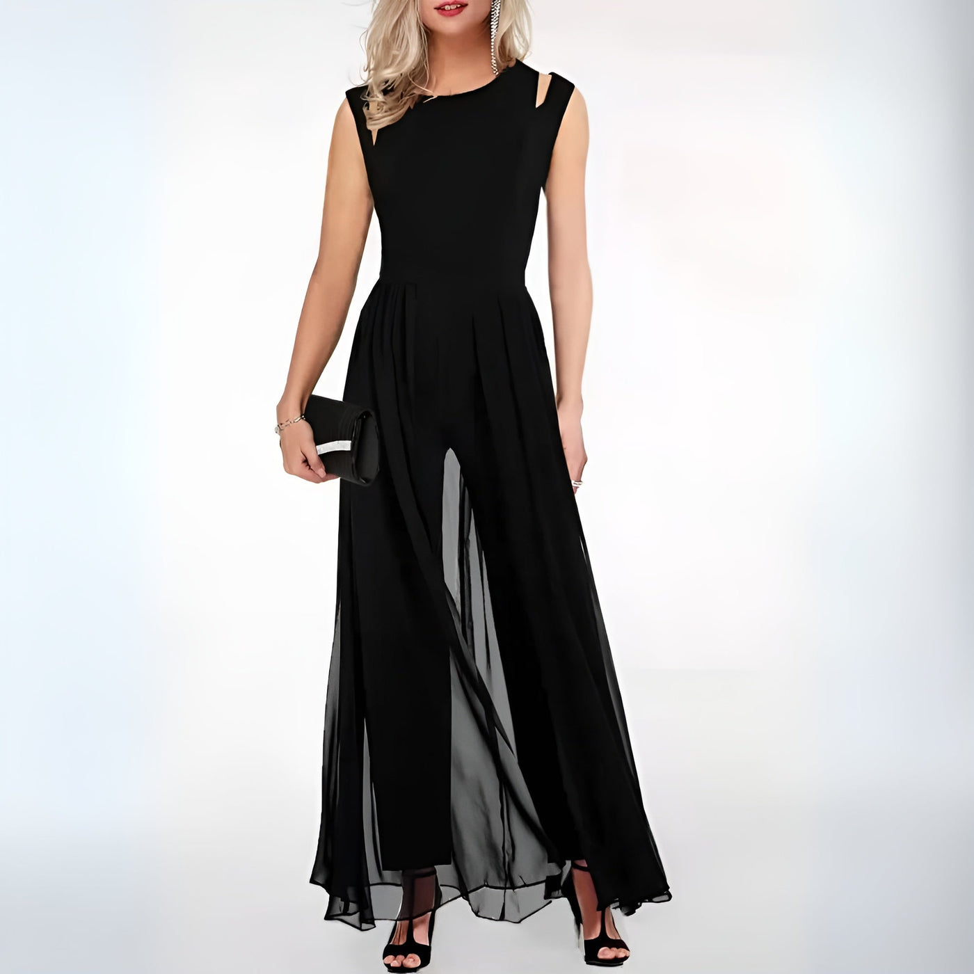 Robe de soirée noire élégante, longue et fluide, avec découpes aux épaules, portée par une femme tenant une pochette noire, chaussures à talons.