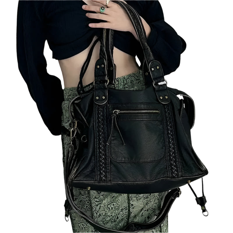 Sac à main en cuir noir élégant avec détails tressés, porté par une personne en tenue chic. Accessoire mode tendance pour femmes.