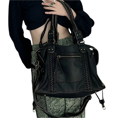 Sac à main en cuir noir élégant avec détails tressés, porté par une personne en tenue chic. Accessoire mode tendance pour femmes.