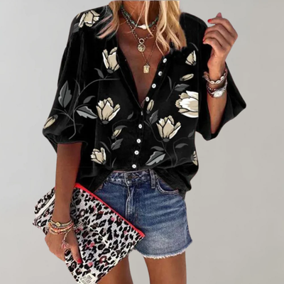 Femme portant une chemise noire à motifs floraux, shorts en jean, tenant une pochette léopard. Mode tendance, style décontracté chic.