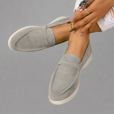 Chaussures mocassins gris clair en daim pour femme, élégantes et confortables, portées avec un jean blanc déchiré. Mode féminine tendance.