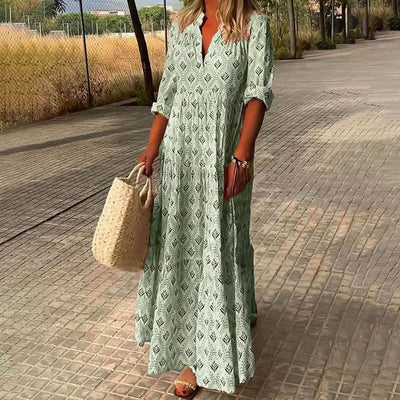 Robe longue verte à motifs géométriques portée par une femme, tenant un sac en osier, sur une allée pavée. Mode estivale, tenue décontractée.