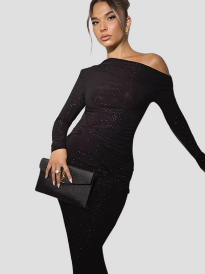 Femme élégante en robe noire asymétrique scintillante, tenant une pochette noire. Mode chic, soirée glamour, style tendance.