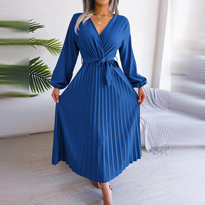 Robe bleue élégante à manches longues et ceinture, plissée, portée par une femme. Mode féminine chic, tendance automne, style décontracté.