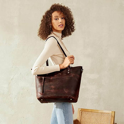 Femme portant un grand sac à main en cuir marron, style cabas, avec une tenue décontractée. Mode féminine, accessoire tendance, sac élégant.
