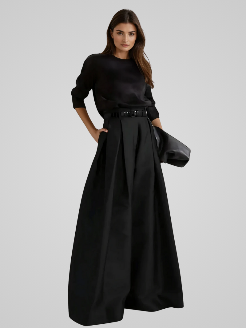 Femme élégante en robe noire longue avec ceinture, manches longues, tenant une pochette. Mode chic, style minimaliste, tenue soirée sophistiquée.