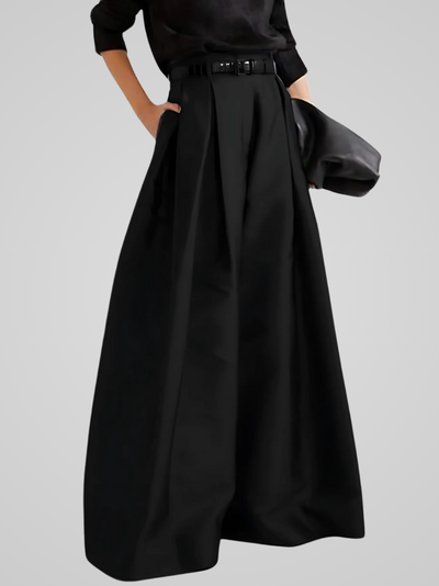 Jupe longue noire élégante avec ceinture, tenue de mode chic, style minimaliste, femme en noir, accessoire sac à main, fond gris clair.