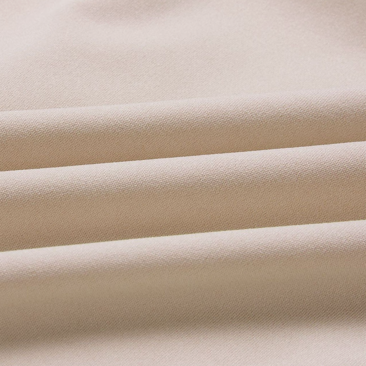 Tissu beige en gros plan, texture douce et plissée, idéal pour couture, mode et décoration intérieure. Matériau textile élégant et polyvalent.