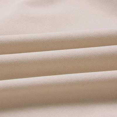 Tissu beige en gros plan, texture douce et plissée, idéal pour couture, mode et décoration intérieure. Matériau textile élégant et polyvalent.