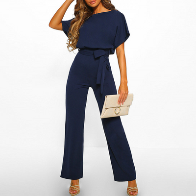Combinaison bleu marine élégante pour femme avec ceinture, tenue chic, pochette beige, sandales à talons, mode féminine tendance.