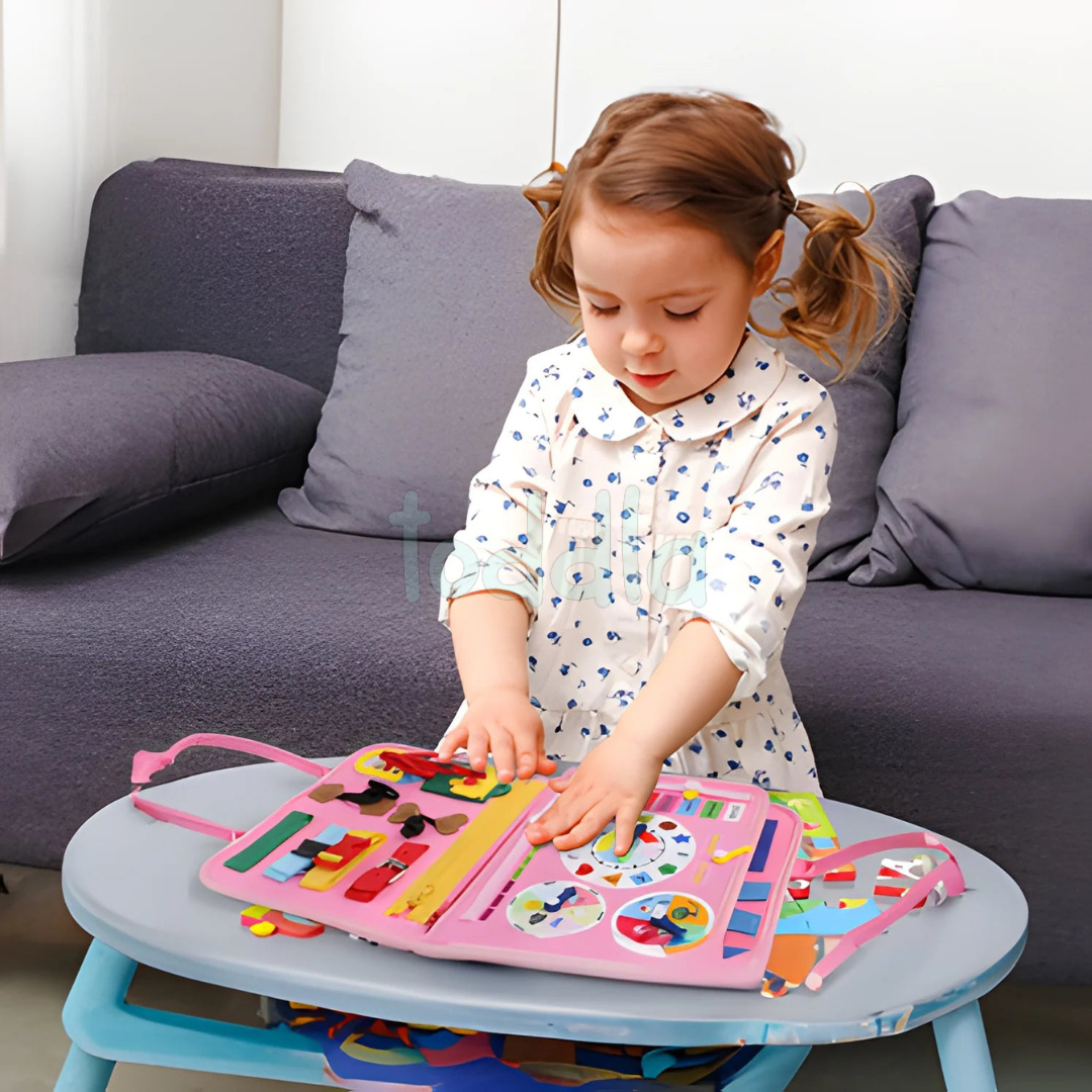 Petite fille jouant avec un livre d'activités éducatif coloré sur une table basse. Jouet interactif pour enfants, développement cognitif, apprentissage ludique.