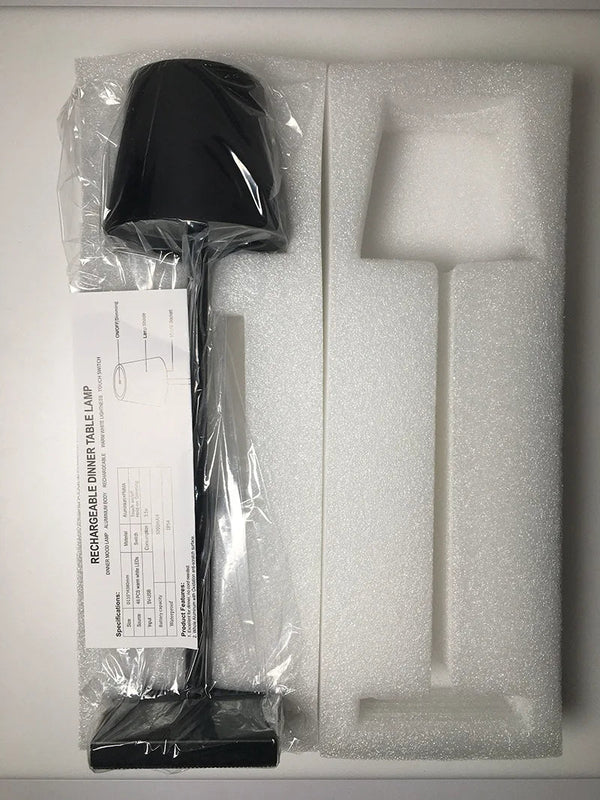 Lampe de table rechargeable noire dans un emballage en mousse, avec manuel d'instructions. Design moderne, éclairage LED, idéale pour bureau.