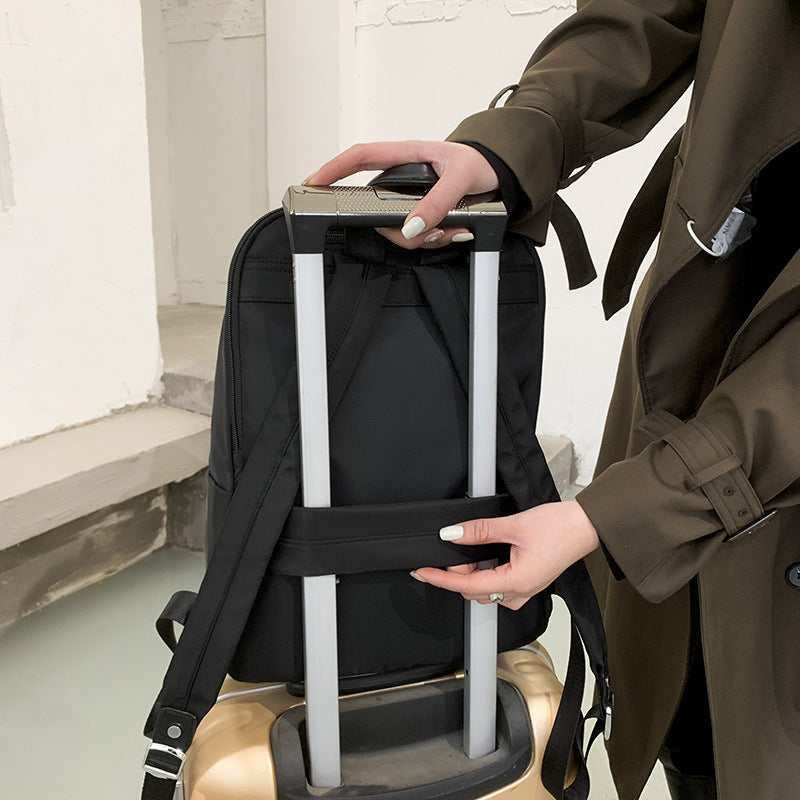 Personne ajustant un sac à dos noir sur une valise à roulettes dorée, intérieur moderne. Voyage, bagage, organisation, transport.