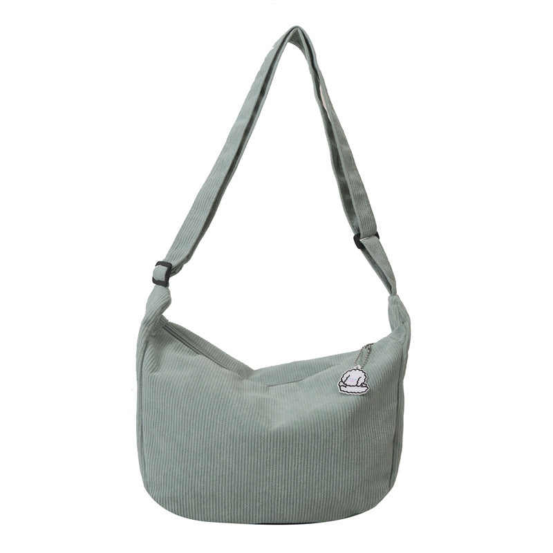 Sac à bandoulière vert en tissu côtelé avec breloque, design moderne et minimaliste, idéal pour un style décontracté et tendance.