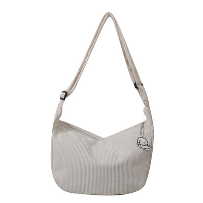Sac à bandoulière beige en toile avec motif brodé, design minimaliste, idéal pour un style décontracté. Accessoire mode tendance et pratique.