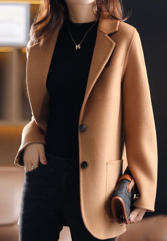 Femme portant un manteau camel élégant, tenue chic avec pull noir, accessoire sac à main en cuir, style automne-hiver tendance.