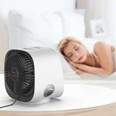 Ventilateur de table blanc moderne sur une table, avec une femme endormie en arrière-plan. Design compact, idéal pour la chambre à coucher.