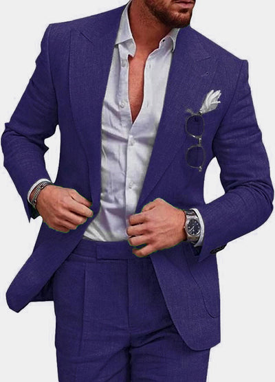 Homme en costume bleu élégant, chemise blanche ouverte, montre-bracelet, lunettes de soleil accrochées, pochette blanche. Mode masculine chic.