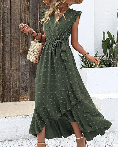 Robe longue verte à volants, motif floral, portée par une femme avec chapeau de paille et sac en osier, style estival chic, fond extérieur.