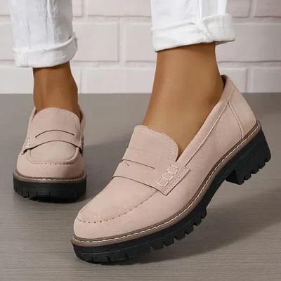 Chaussures mocassins beiges pour femme avec semelles épaisses noires, portées avec un pantalon blanc. Mode féminine, style décontracté élégant.