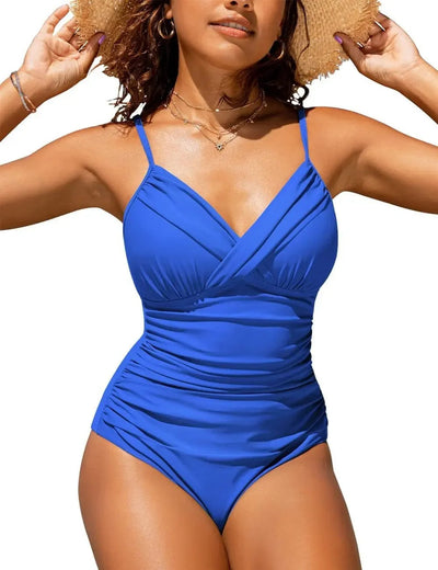 Femme en maillot de bain bleu une pièce, bretelles fines, portant un chapeau de paille, posant en extérieur. Mode plage été, style élégant.