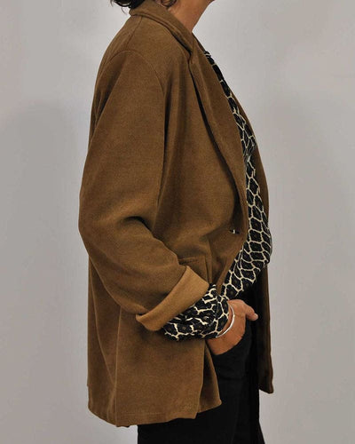 Veste marron élégante pour femme, manches retroussées, portée sur un pull à motif animalier noir et blanc, style chic et décontracté.