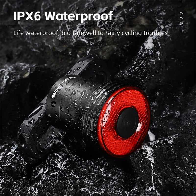 Feu arrière de vélo étanche IPX6, rouge, sur fond de rochers mouillés. Accessoire de sécurité pour cyclisme sous la pluie.