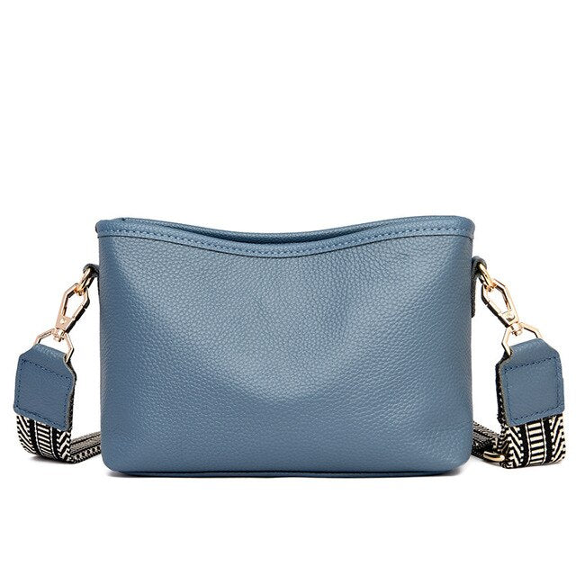 Sac à main en cuir bleu avec bandoulière amovible à motifs noirs et blancs, fermoirs dorés. Accessoire mode élégant et tendance.